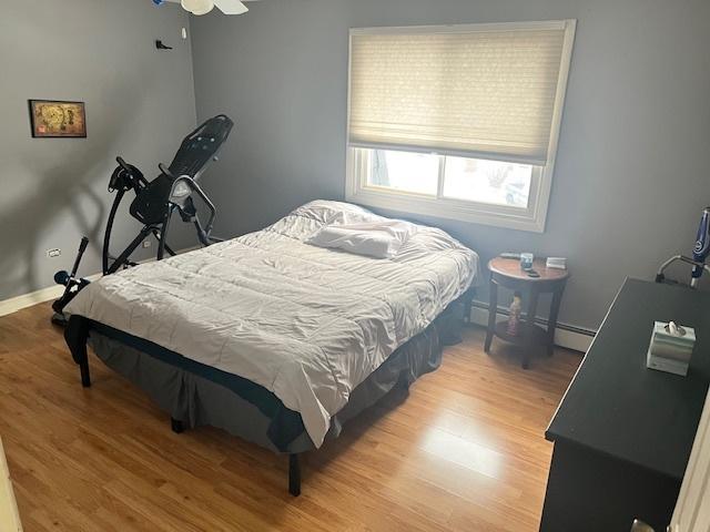 bedroom featuring baseboard heating, ceiling fan, and light hardwood / wood-style flooring