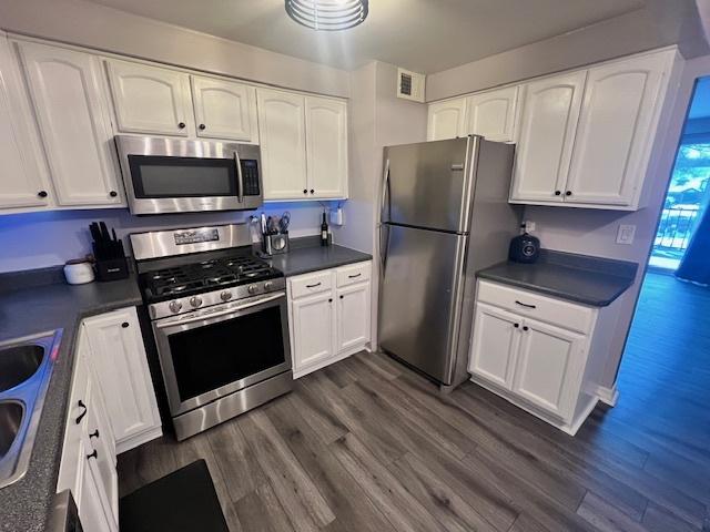 kitchen featuring sink, white cabinetry, dark wood-type flooring, and appliances with stainless steel finishes