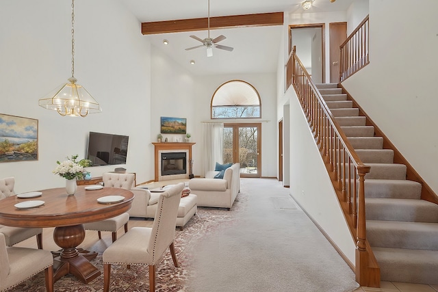 carpeted living room with ceiling fan with notable chandelier, a high ceiling, and beamed ceiling