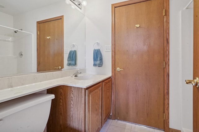 bathroom with toilet, vanity, tile patterned floors, and walk in shower