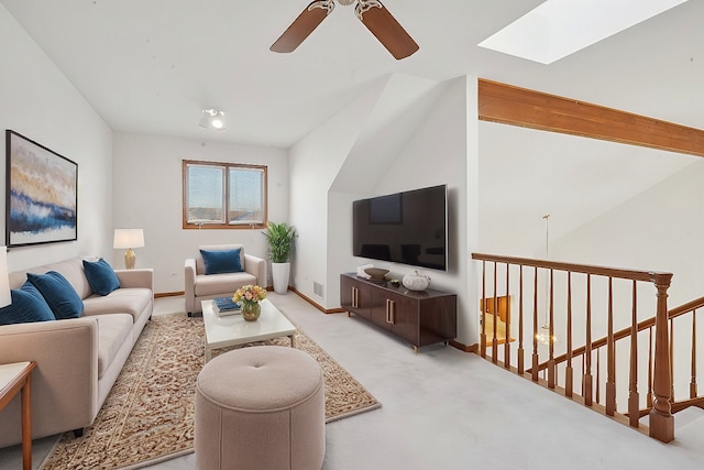 carpeted living room featuring ceiling fan, beam ceiling, and a skylight