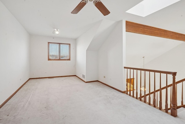 additional living space with ceiling fan, lofted ceiling with skylight, and light carpet