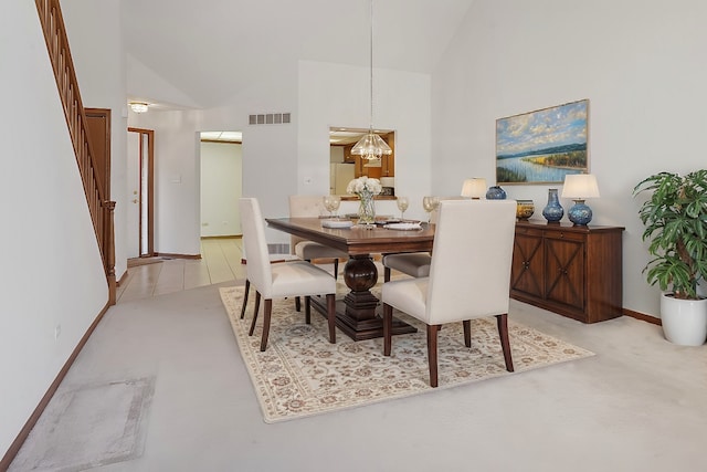 carpeted dining space with a chandelier and high vaulted ceiling