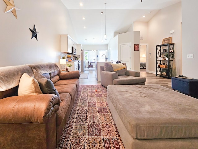 living room with light hardwood / wood-style floors and high vaulted ceiling