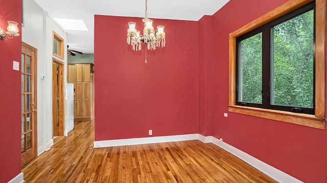 unfurnished dining area featuring an inviting chandelier and wood-type flooring