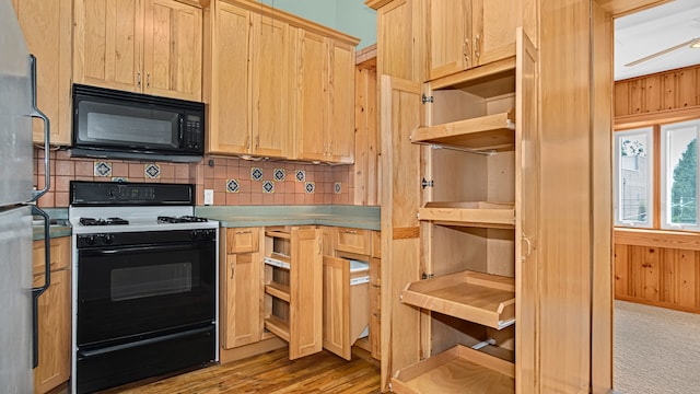 kitchen featuring stainless steel refrigerator, wooden walls, decorative backsplash, light brown cabinetry, and gas range
