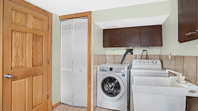 laundry area featuring sink, light tile patterned floors, washing machine and dryer, and cabinets