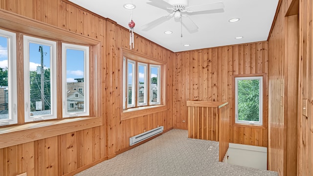 interior space featuring a baseboard radiator, carpet flooring, ceiling fan, and wood walls