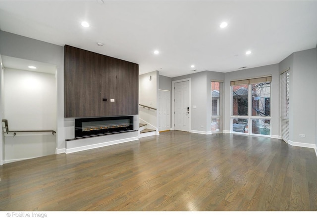 unfurnished living room featuring dark hardwood / wood-style flooring and a large fireplace