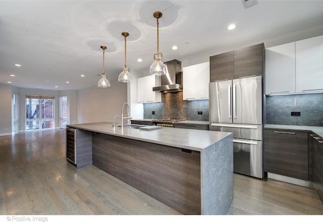 kitchen with stainless steel appliances, white cabinetry, wall chimney exhaust hood, and hanging light fixtures