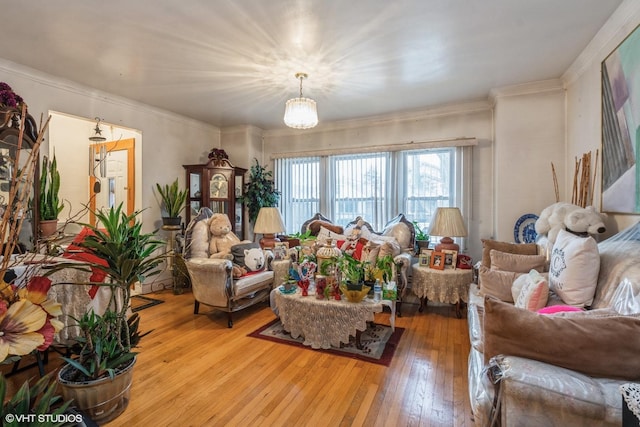 living room featuring ornamental molding, a chandelier, and light hardwood / wood-style flooring