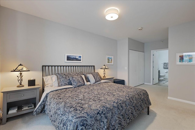 bedroom featuring ensuite bath, a closet, and light carpet