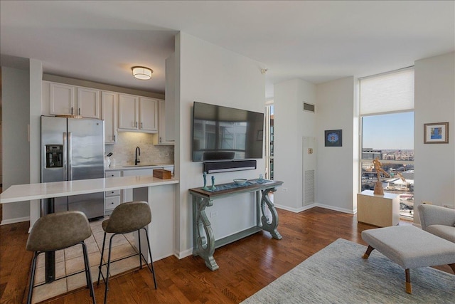 kitchen featuring sink, white cabinets, a breakfast bar area, backsplash, and stainless steel refrigerator with ice dispenser