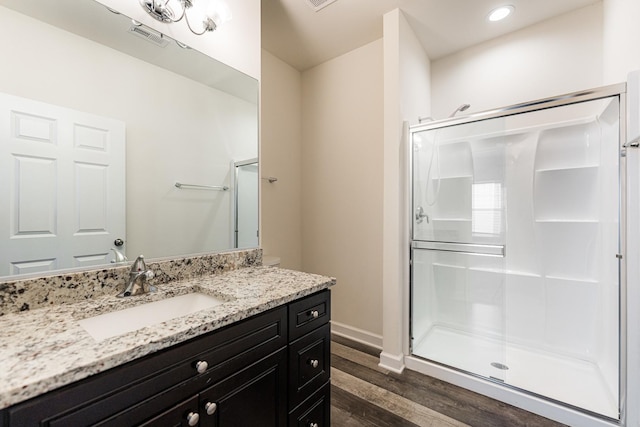 bathroom featuring wood-type flooring, a shower with door, and vanity