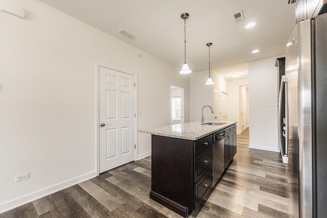 kitchen featuring pendant lighting, sink, appliances with stainless steel finishes, an island with sink, and light stone counters