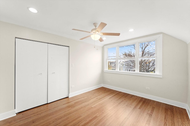 unfurnished bedroom featuring ceiling fan, light hardwood / wood-style flooring, a closet, and vaulted ceiling