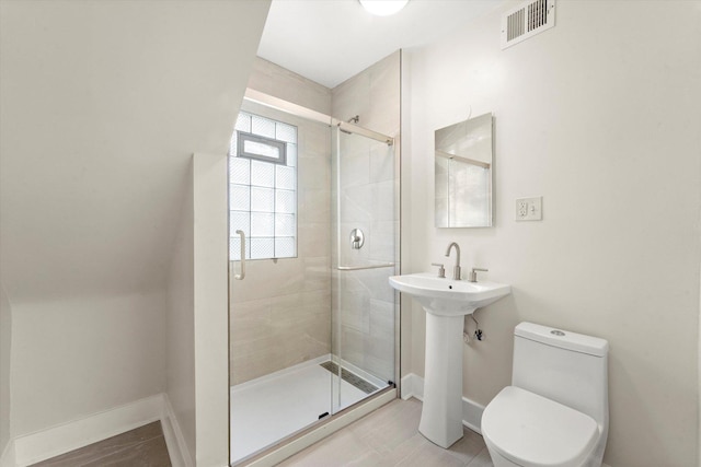 bathroom featuring toilet, tile patterned flooring, and a shower with door