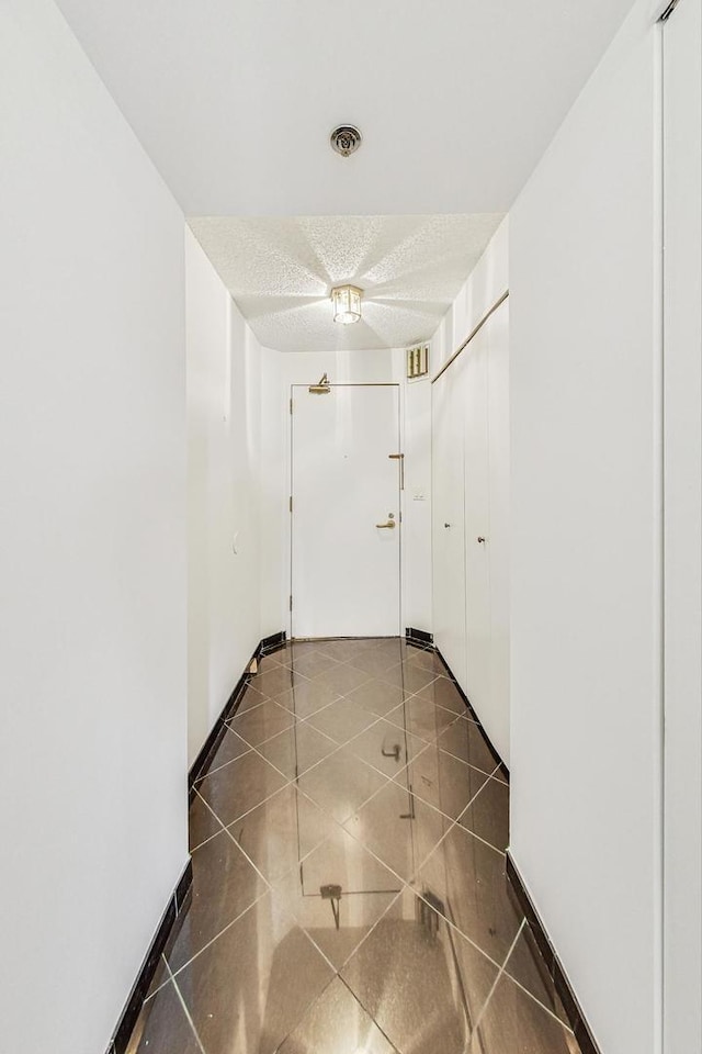 corridor with dark tile patterned flooring and a textured ceiling