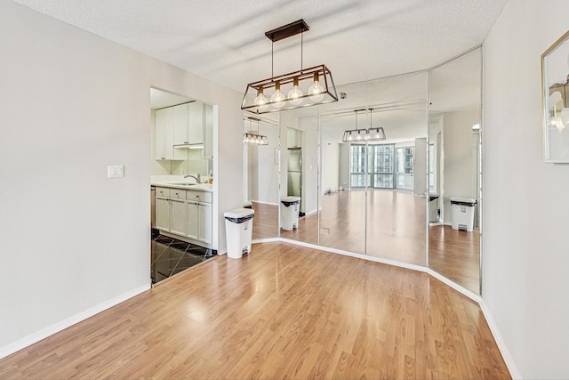 unfurnished dining area featuring sink, a textured ceiling, and hardwood / wood-style floors