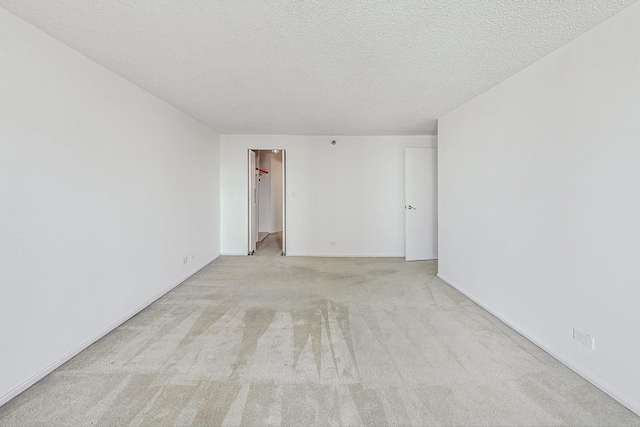 empty room with light colored carpet and a textured ceiling