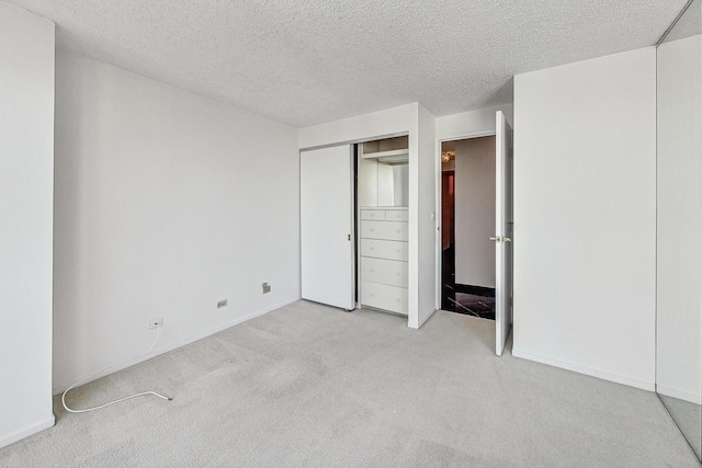 unfurnished bedroom featuring a textured ceiling and light carpet