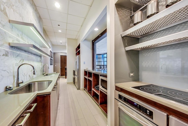 kitchen featuring tasteful backsplash, a drop ceiling, sink, and stainless steel appliances