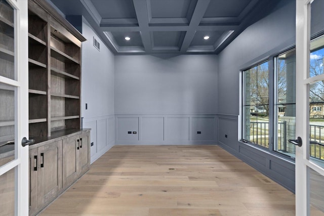 spare room featuring beamed ceiling, light wood-type flooring, built in features, and coffered ceiling