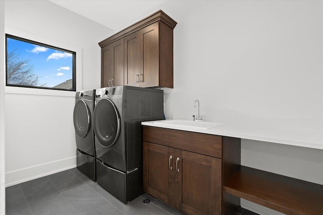 laundry room featuring washer and dryer, dark tile patterned floors, sink, and cabinets