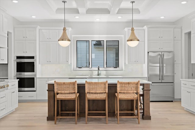 kitchen featuring stainless steel appliances, sink, white cabinetry, a center island, and backsplash