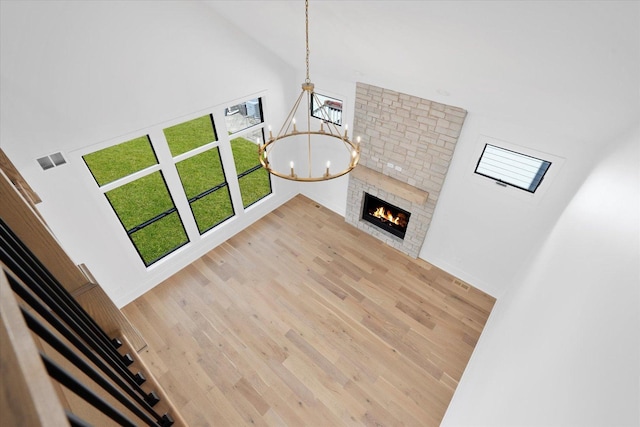 unfurnished living room featuring a notable chandelier, hardwood / wood-style floors, and a fireplace