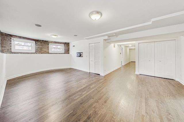 spare room featuring hardwood / wood-style flooring and brick wall