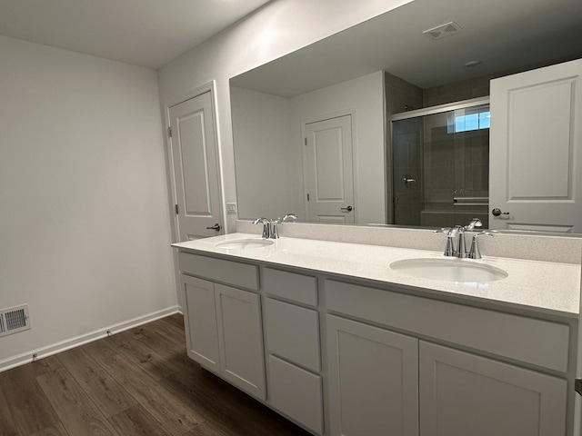 bathroom with hardwood / wood-style flooring, vanity, and an enclosed shower