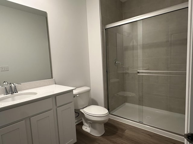 bathroom with walk in shower, vanity, toilet, and hardwood / wood-style flooring