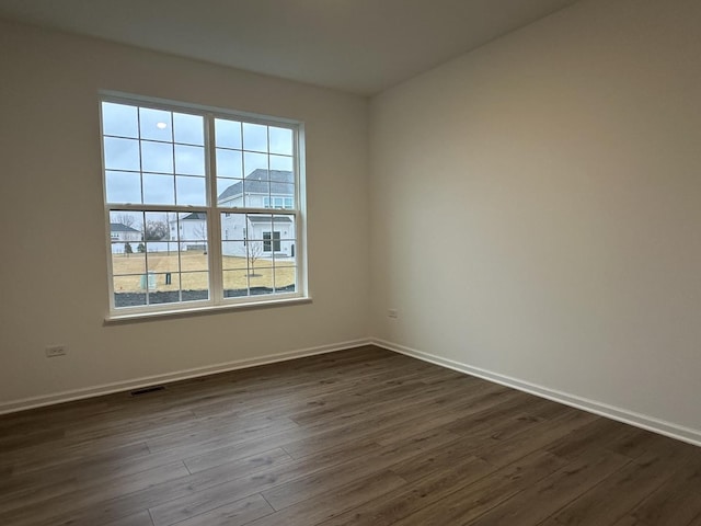 spare room with dark hardwood / wood-style flooring and plenty of natural light