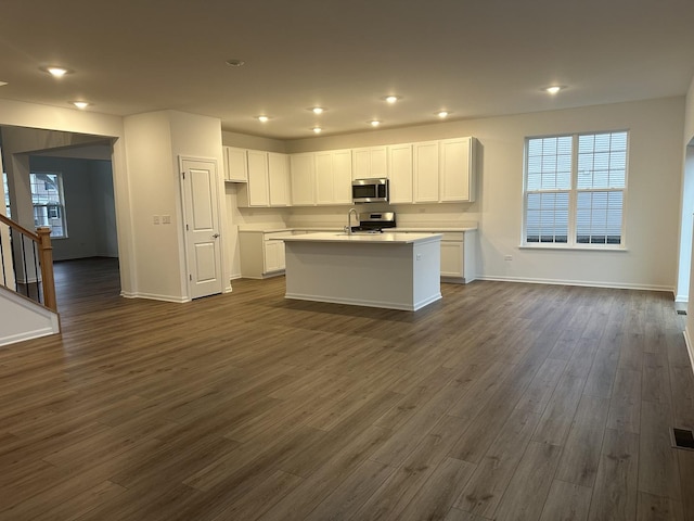 kitchen featuring white cabinetry, a center island with sink, stainless steel appliances, dark hardwood / wood-style flooring, and sink