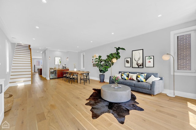 living room with crown molding and light wood-type flooring