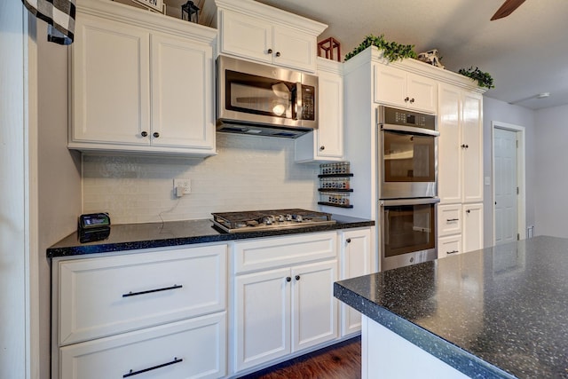 kitchen with ceiling fan, appliances with stainless steel finishes, decorative backsplash, dark hardwood / wood-style flooring, and white cabinets