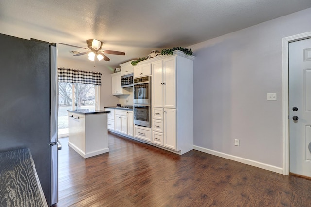 kitchen featuring dark wood-type flooring, appliances with stainless steel finishes, white cabinetry, and ceiling fan