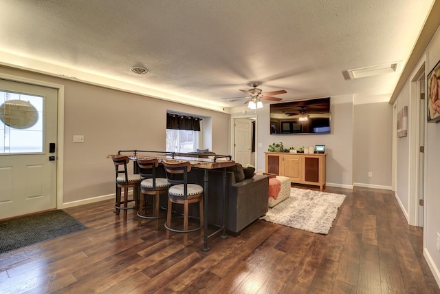 living room featuring a textured ceiling, dark wood-type flooring, and ceiling fan