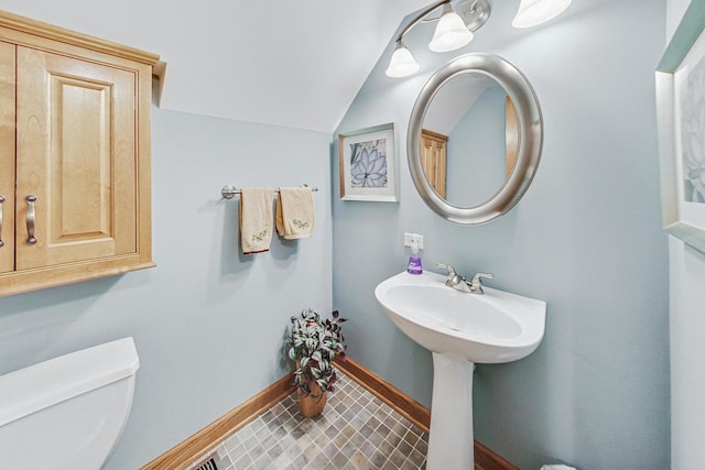 bathroom with tile patterned flooring, vaulted ceiling, and toilet