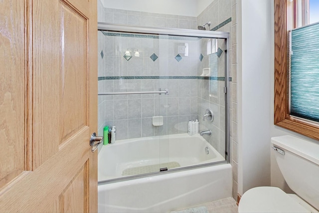 bathroom with toilet and shower / bath combination with glass door