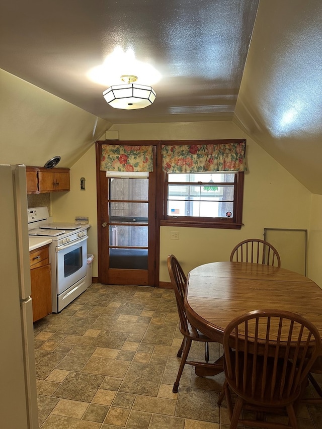 dining area featuring a textured ceiling and vaulted ceiling