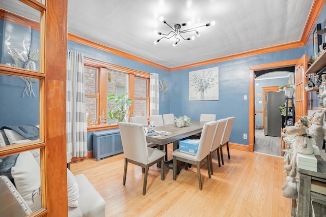 dining area with radiator, ornamental molding, a chandelier, and light hardwood / wood-style flooring