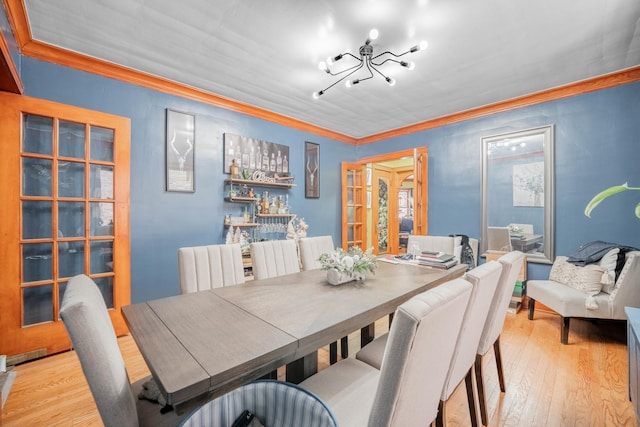 dining space featuring an inviting chandelier, ornamental molding, and light wood-type flooring