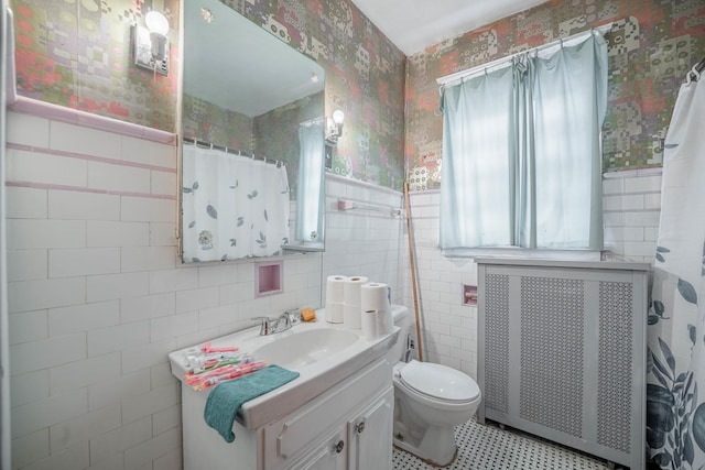 bathroom with toilet, tile walls, vanity, and radiator heating unit