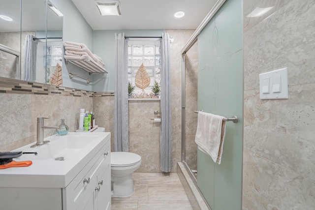 bathroom with walk in shower, vanity, tile walls, and toilet