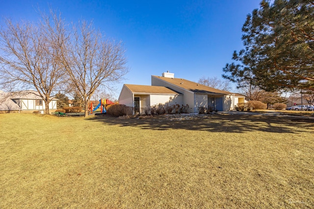 back of property featuring a lawn and a playground