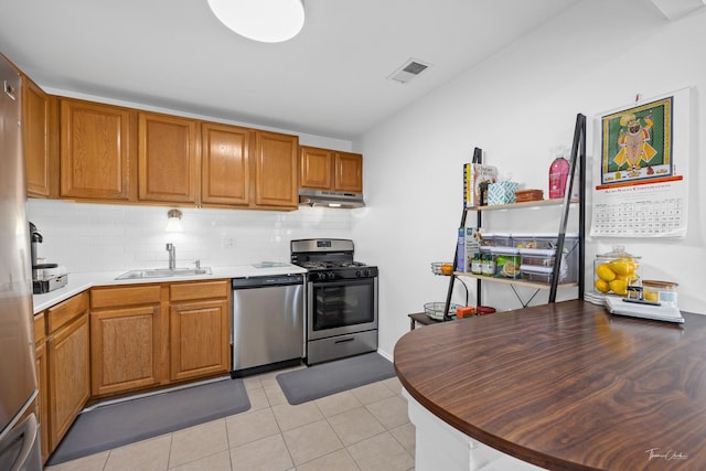 kitchen with light tile patterned floors, stainless steel appliances, backsplash, and sink