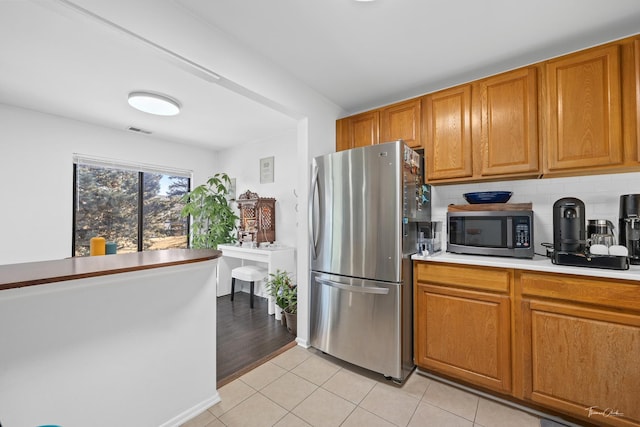 kitchen featuring tasteful backsplash, light tile patterned floors, and stainless steel appliances