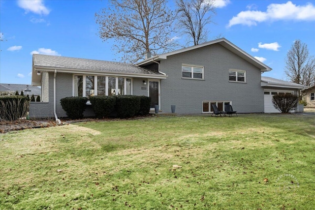 rear view of house featuring a lawn and a garage